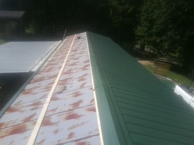 Old rusted panels beside newly installed green metal roofing — Wind Damage Roof Repair by Roofing Brothers in Marion Station