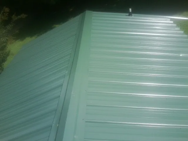 New green metal panels meeting at the ridge of a roof — Flat Roof Repair work by our crew in Marion Station