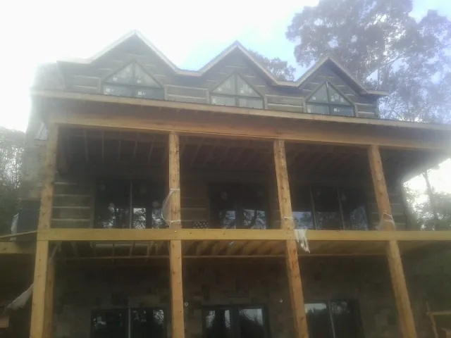 Dormers and porch framing on a large log home under construction — Roof Coating work by our crew in Marion Station