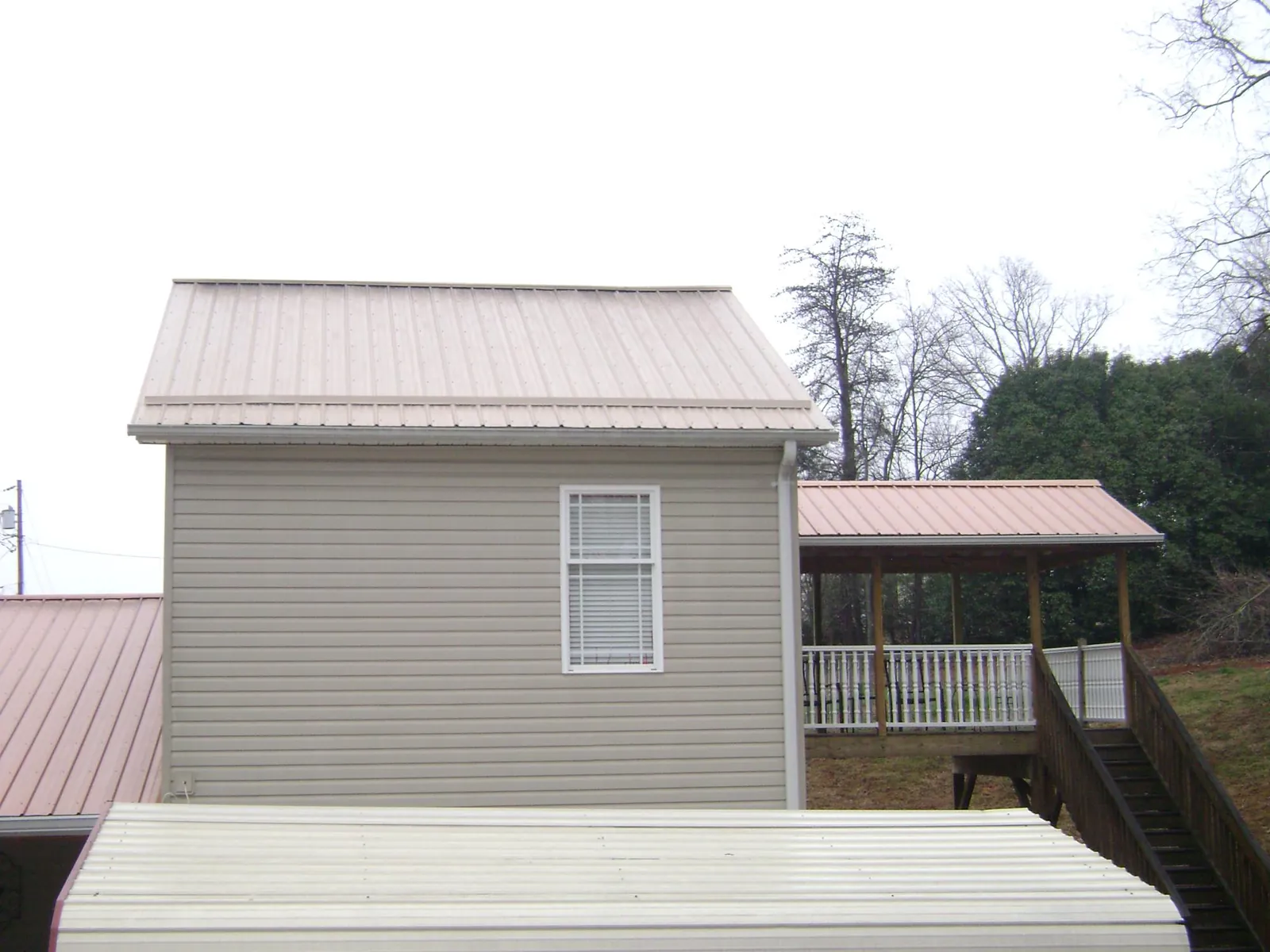 Tan metal roofs on a two story addition and attached porch, from a Roof Replacement job in Marion Station